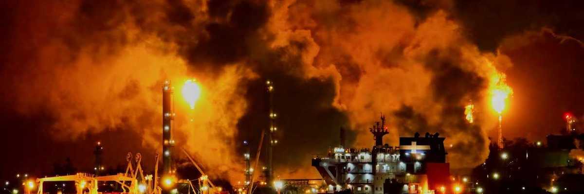 Petrochemical or refinery facility venting methane at night enveloped in toxic smoke