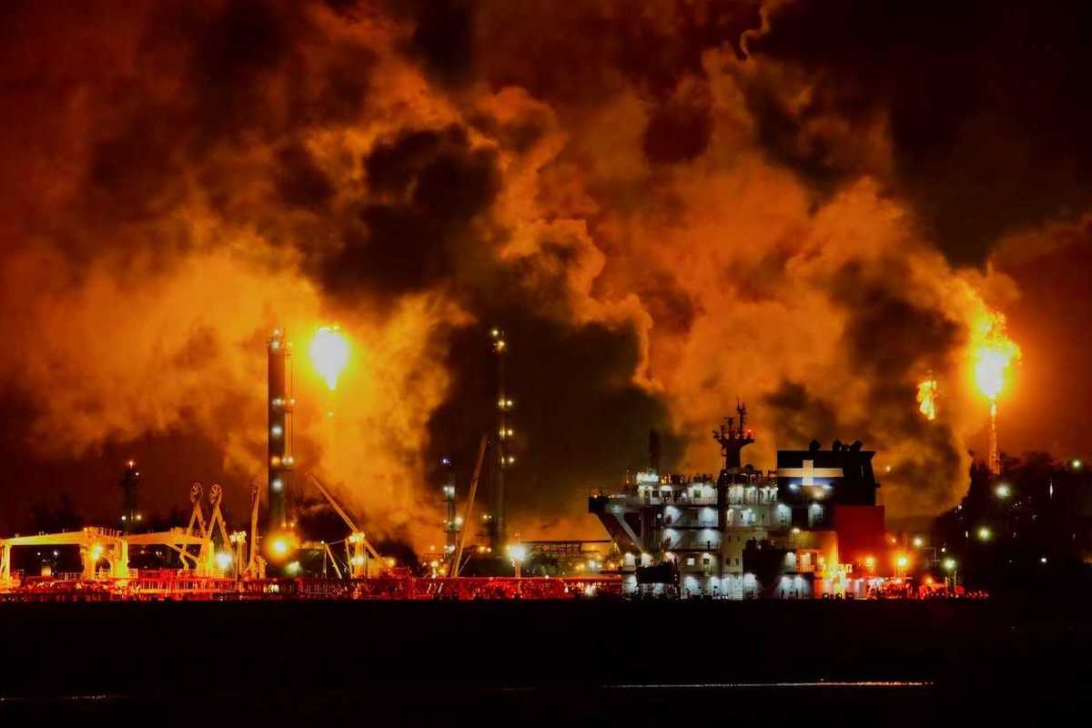 Petrochemical or refinery facility venting methane at night enveloped in toxic smoke