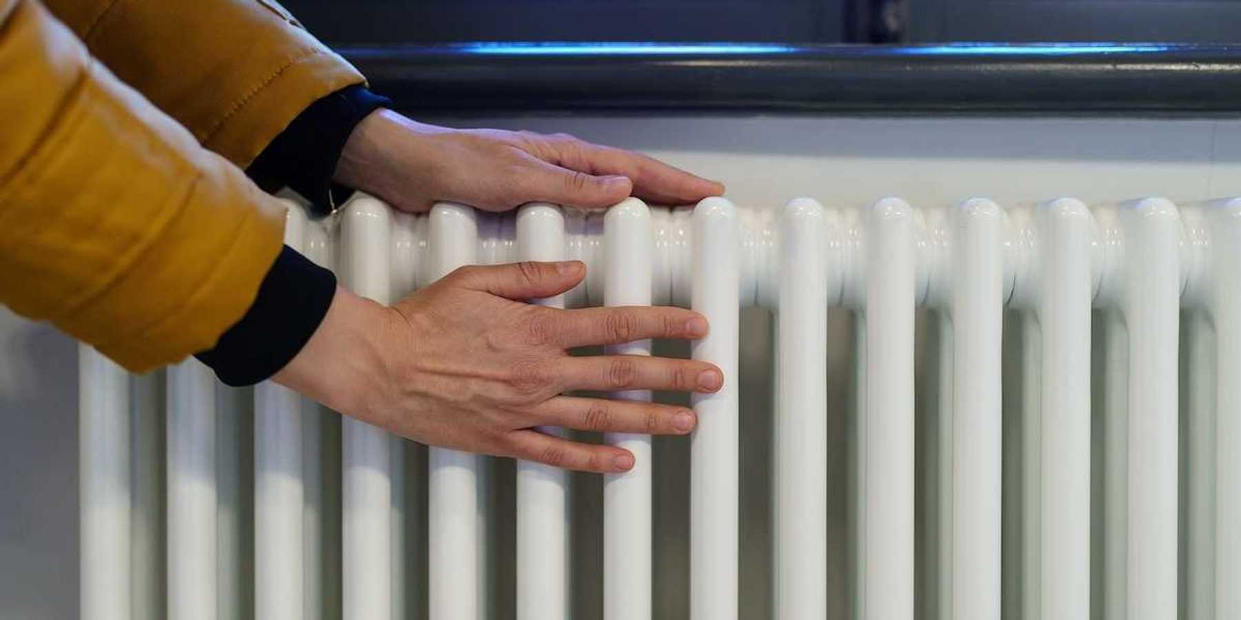 Photo of hands being warmed on an old-fashioned style radiator.