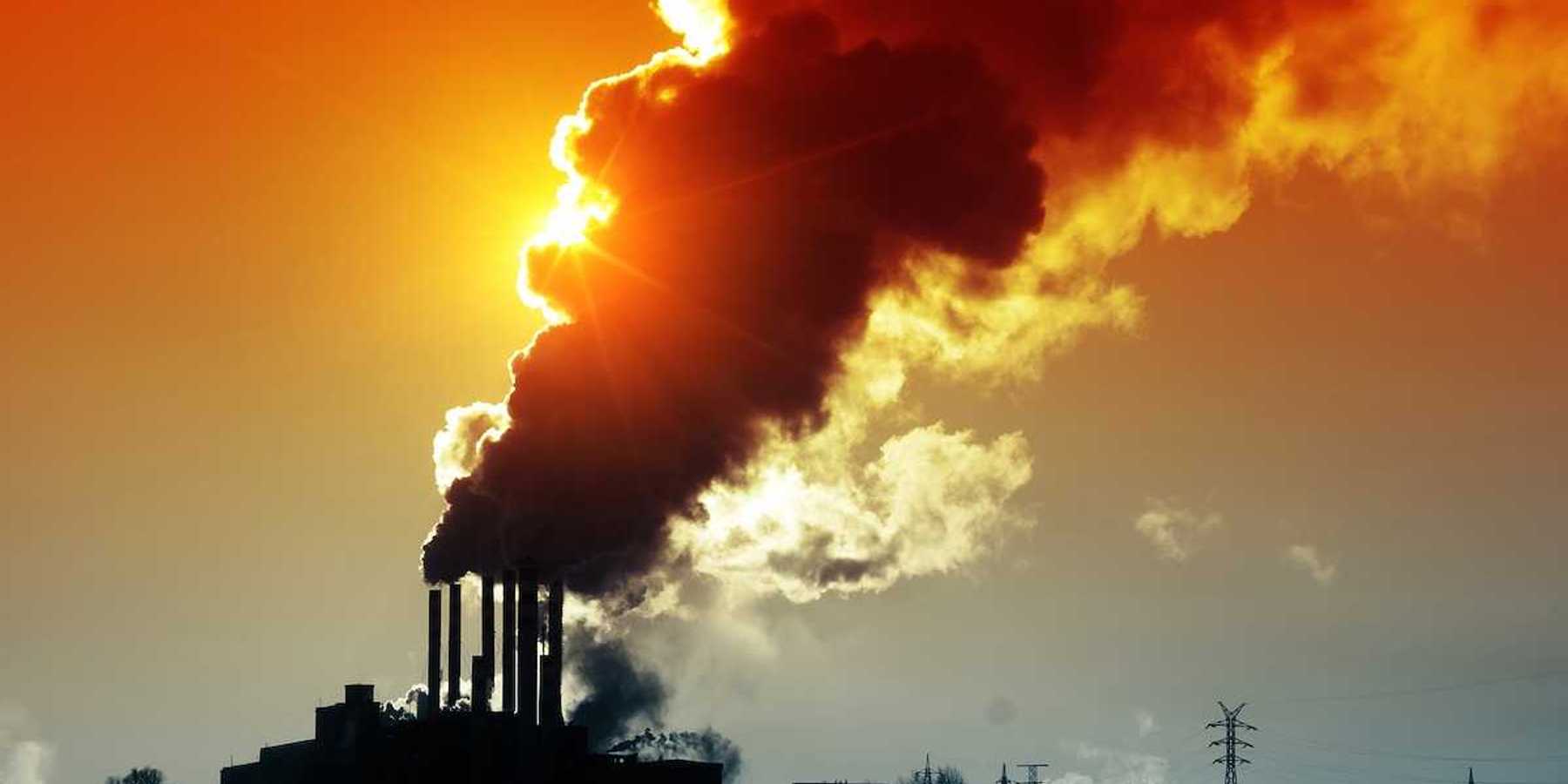 Power plant discharging smoke and dirty orange air obscuring the sun