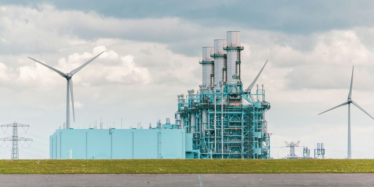 Power plant with wind turbine in the background.