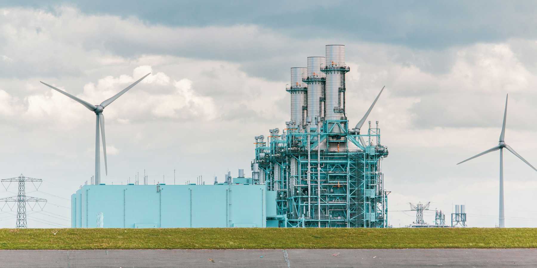 Power plant with wind turbine in the background.