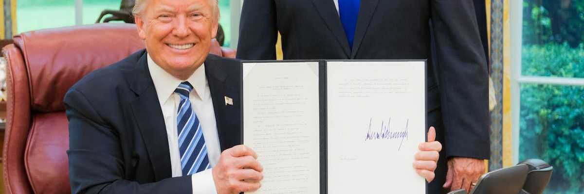 President Trump smiling while displaying a recently signed executive order