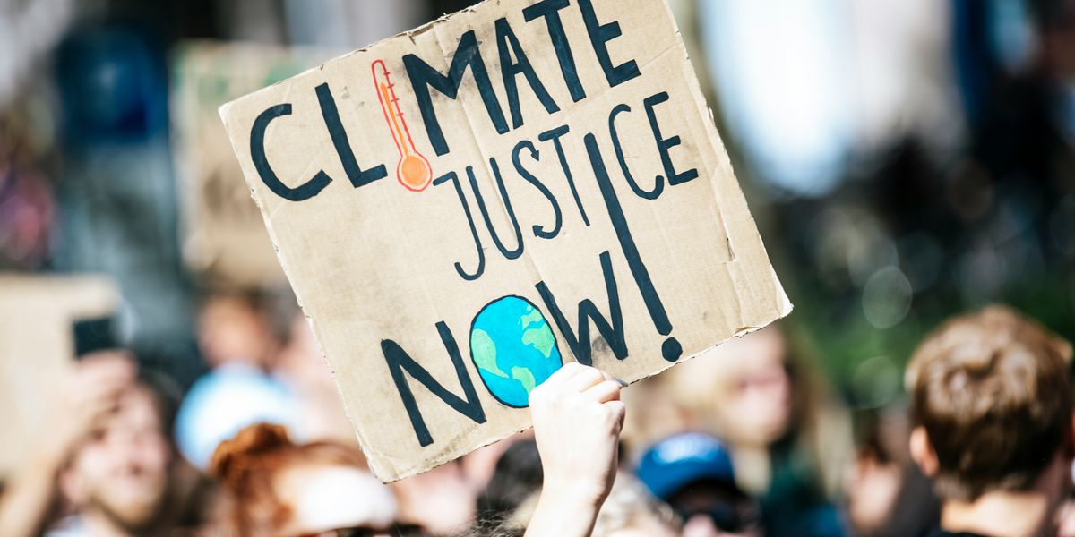 protester sign that says "Climate Justice Now"