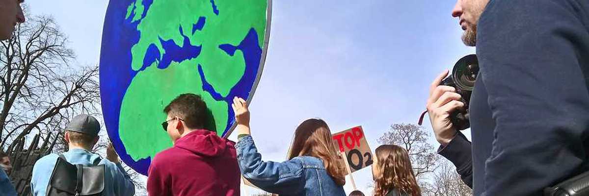 Protesters carrying a large sign in the shape of the Earth