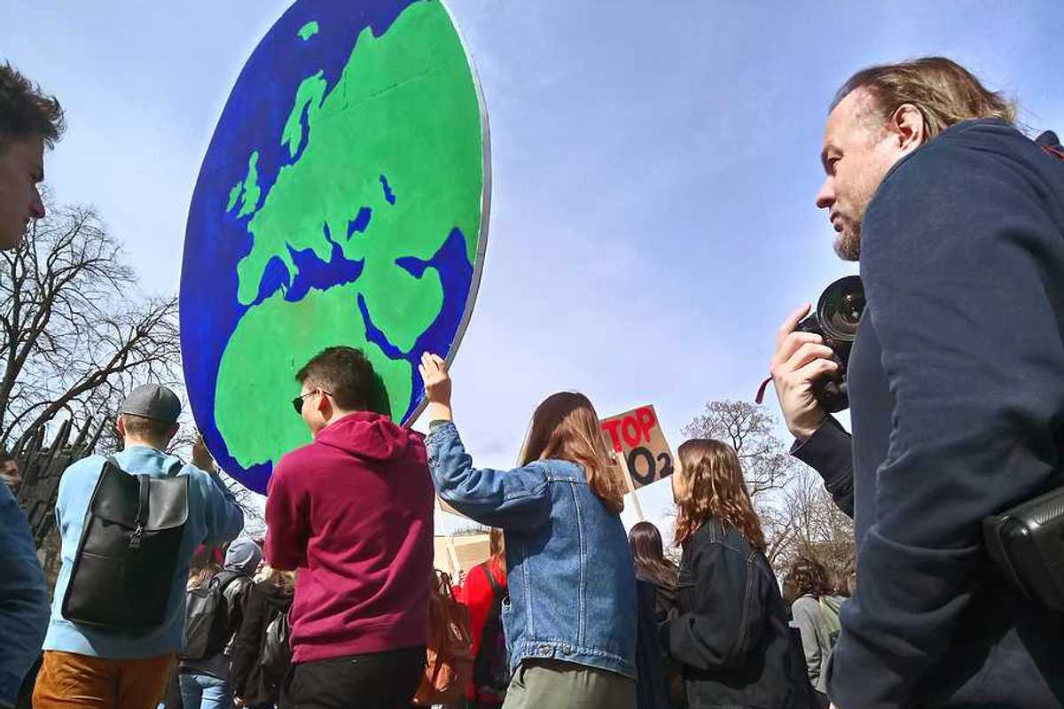 Protesters carrying a large sign in the shape of the Earth