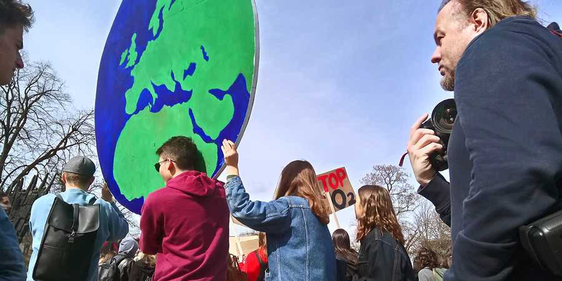 Protesters carrying a large sign in the shape of the Earth