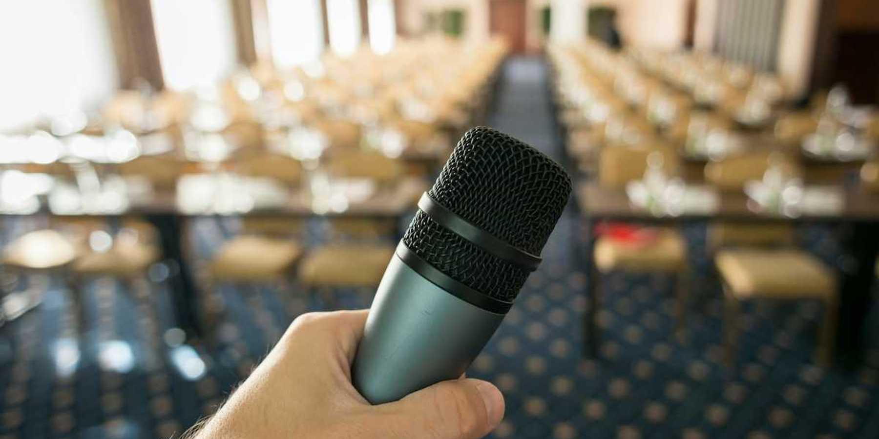 Public hearing space with mic in foreground and empty seats in a blurry background