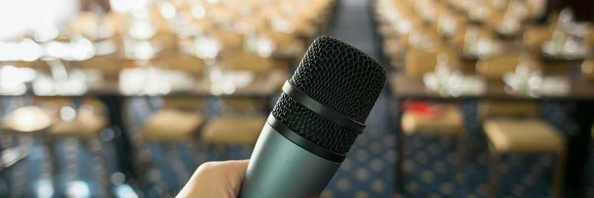 Public hearing space with microphone in foreground and empty seats in a blurry background