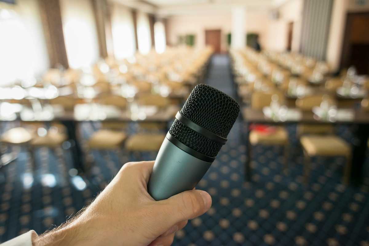 Public hearing space with microphone in foreground and empty seats in a blurry background
