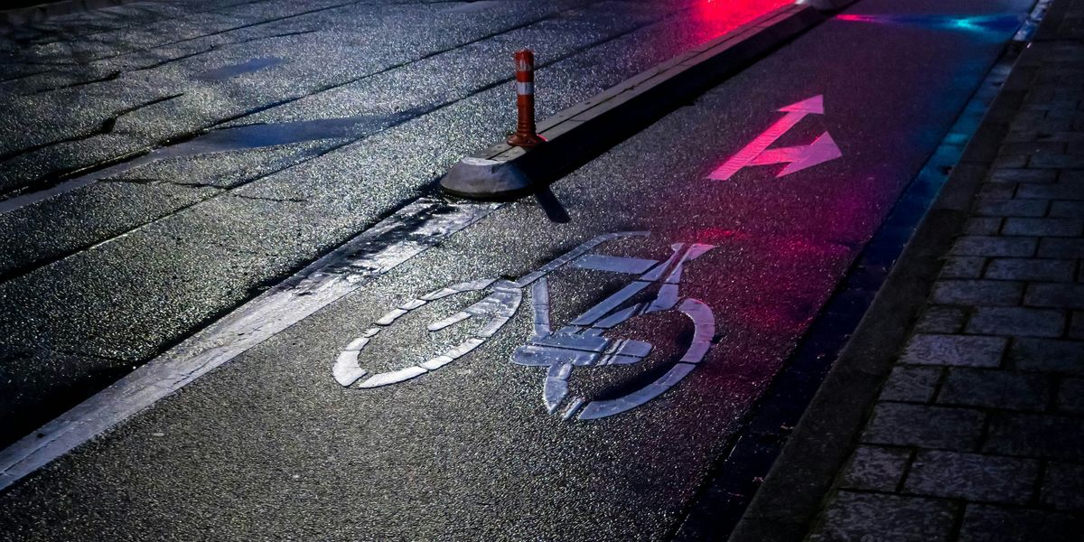 red and black traffic light on gray asphalt road with bike lane.