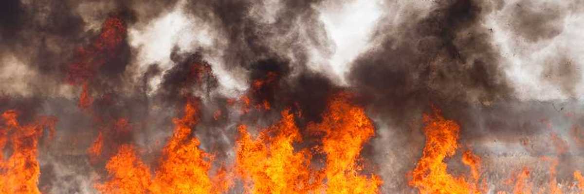 Red and orange flames with black smoke in the distance