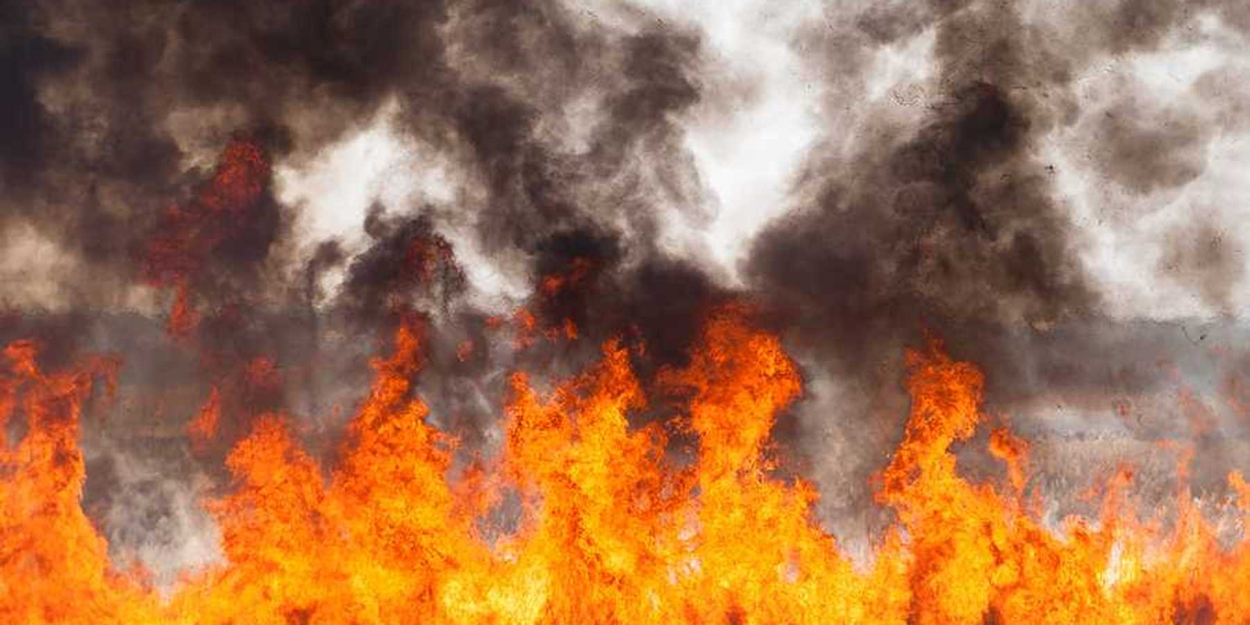 Red and orange flames with black smoke in the distance