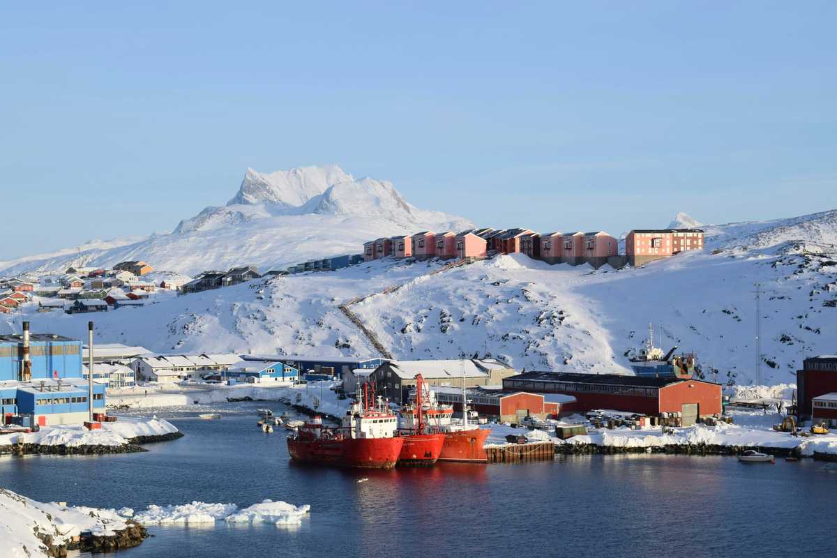 red and white ship on sea near snow covered mountain during daytime