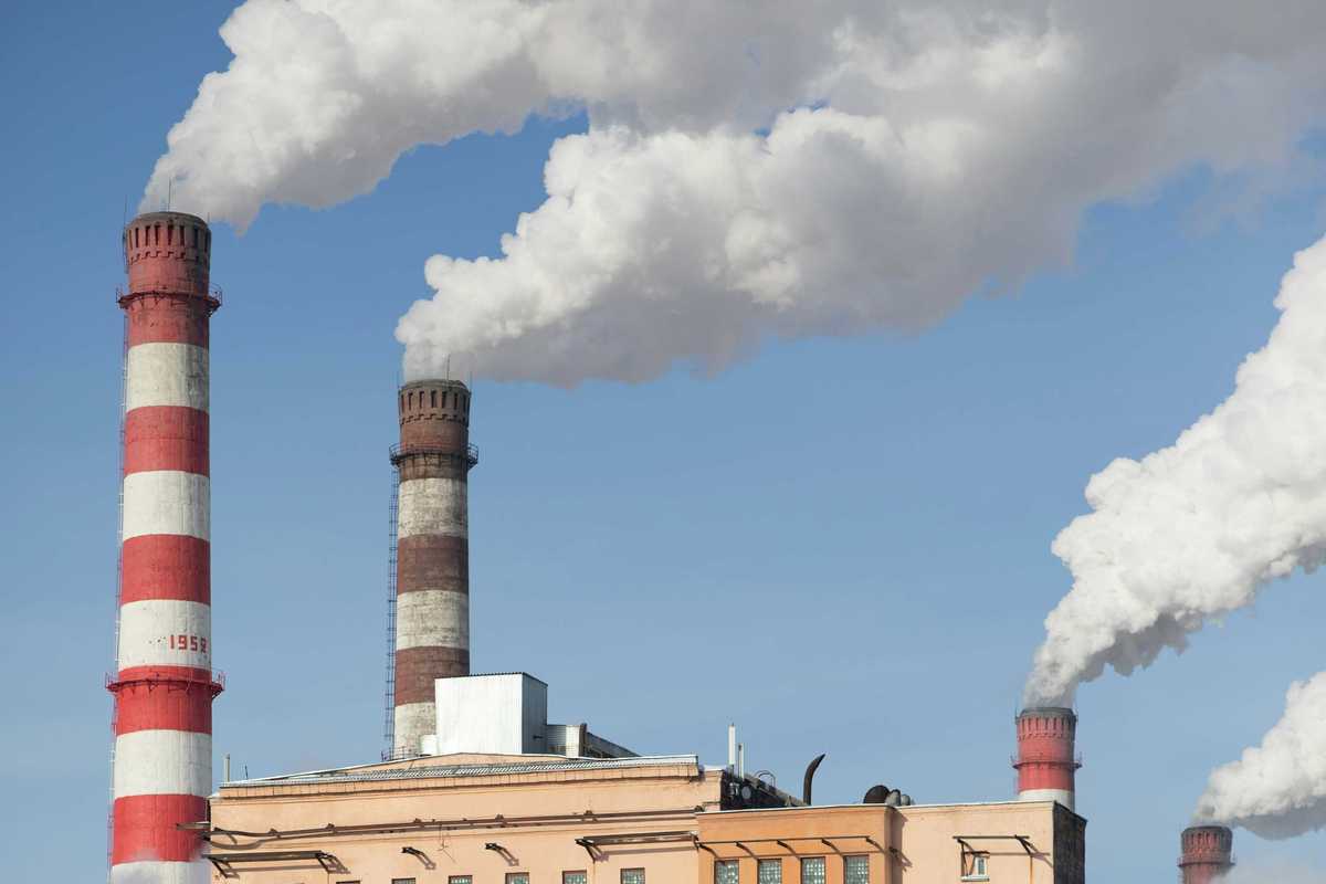 Red and white striped power plant smokestacks with billowing smoke emitting from the top