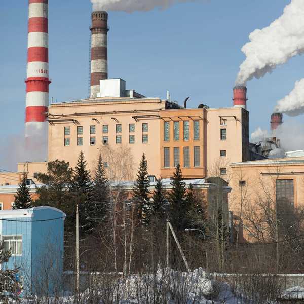 Red and white striped power plant smokestacks with billowing smoke emitting from the top