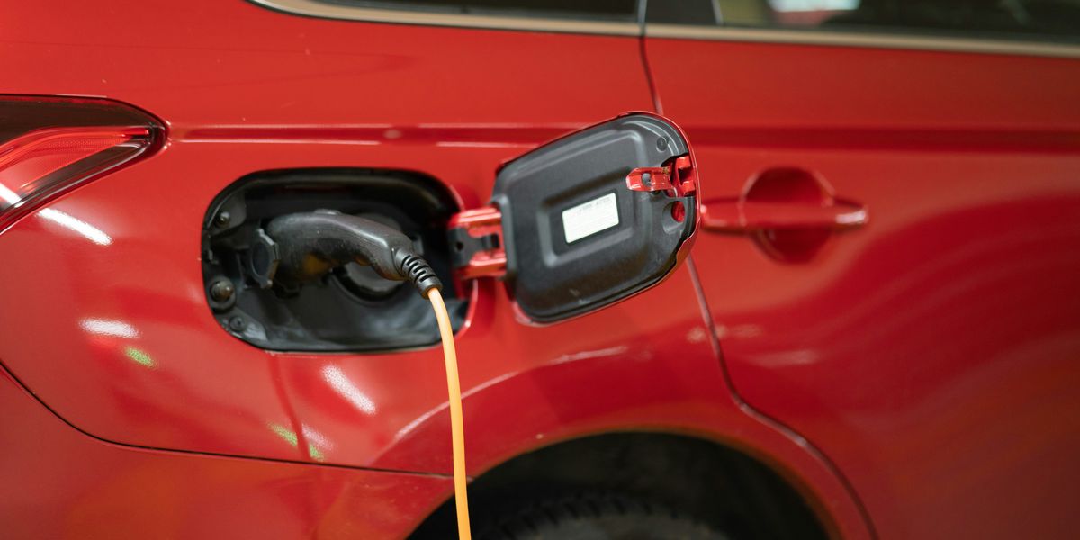 Red car with EV charger hooked up to it.