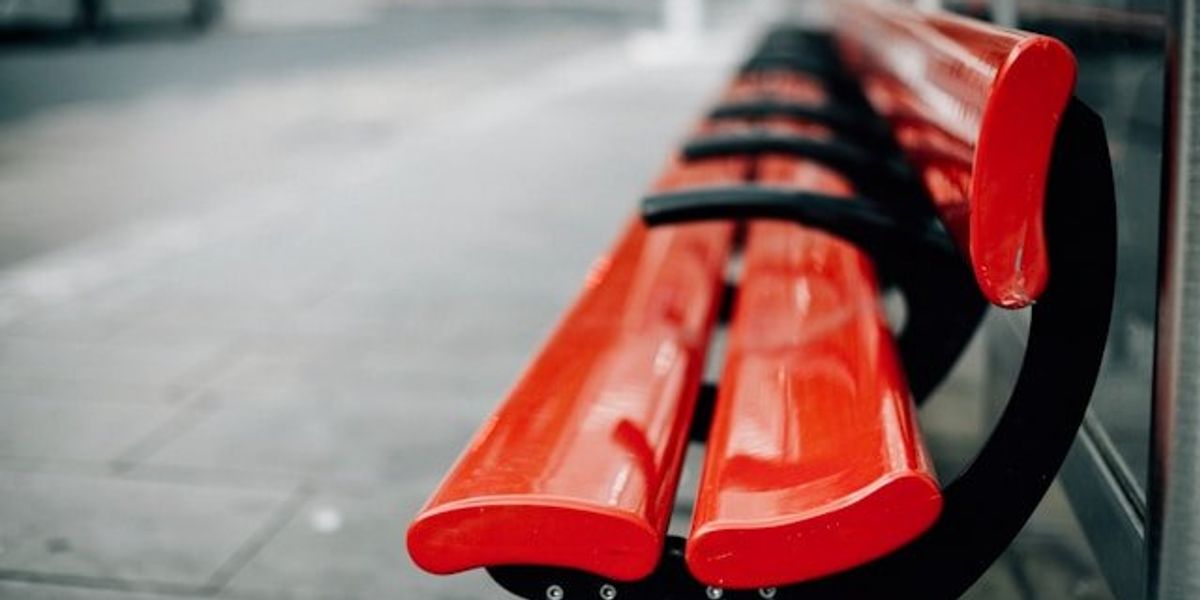 Red city benches on a sidewalk.