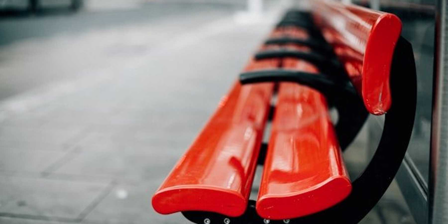 Red city benches on a sidewalk.