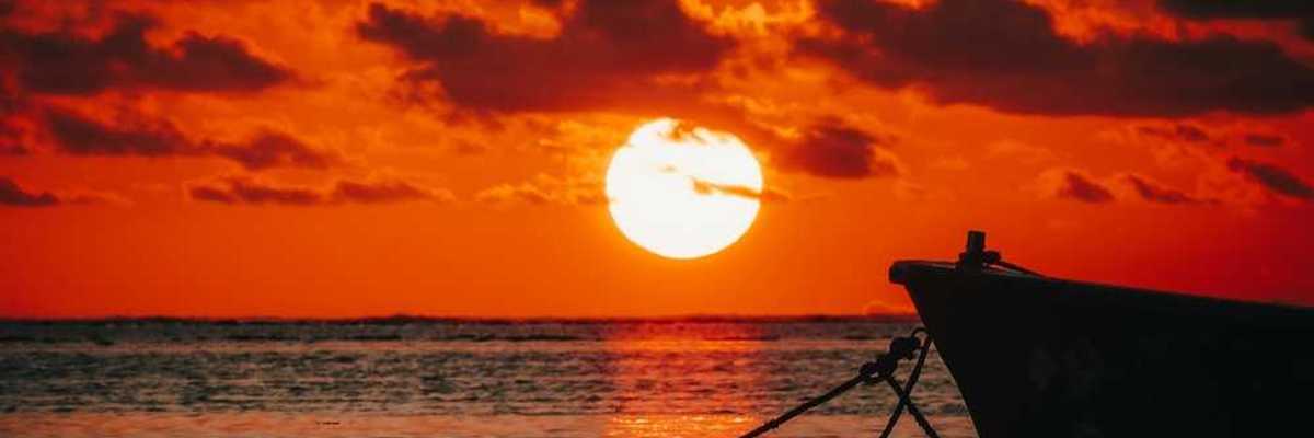 Red sunset over the ocean backlighting a tied-off skiff