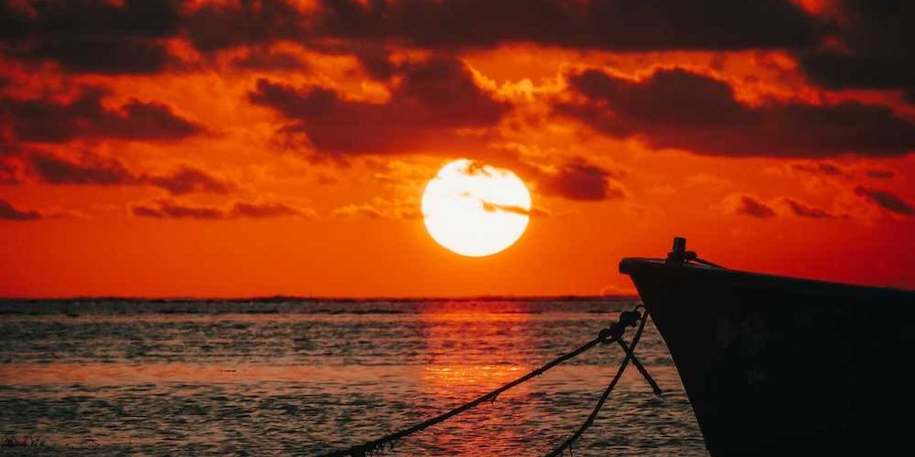 Red sunset over the ocean backlighting a tied-off skiff