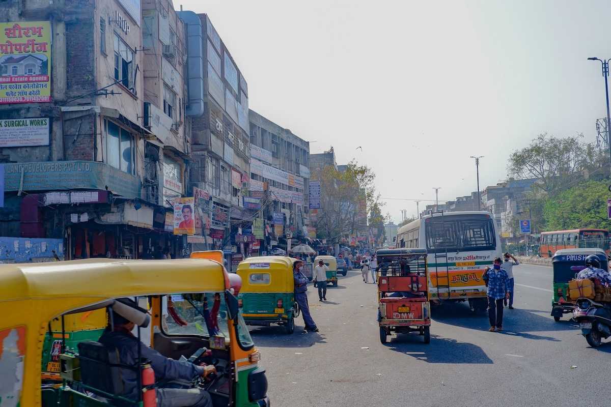 Rickshaws, scooters, busses, and pedestrians on a Delhi street