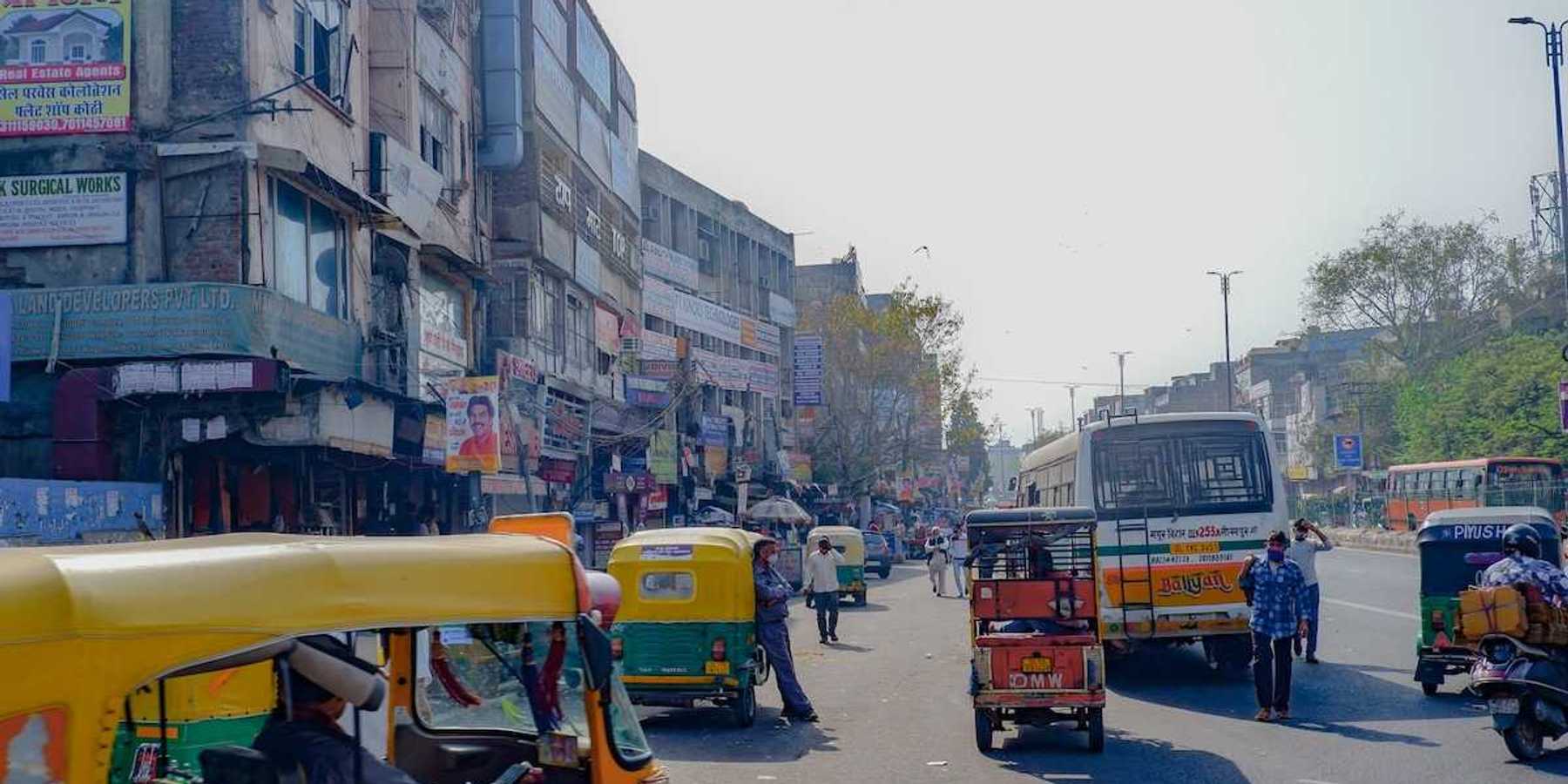 Rickshaws, scooters, busses, and pedestrians on a Delhi street