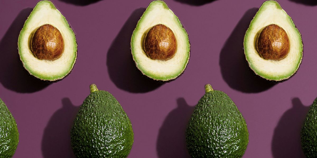 Rows of avocados both whole and halved on a purple background.