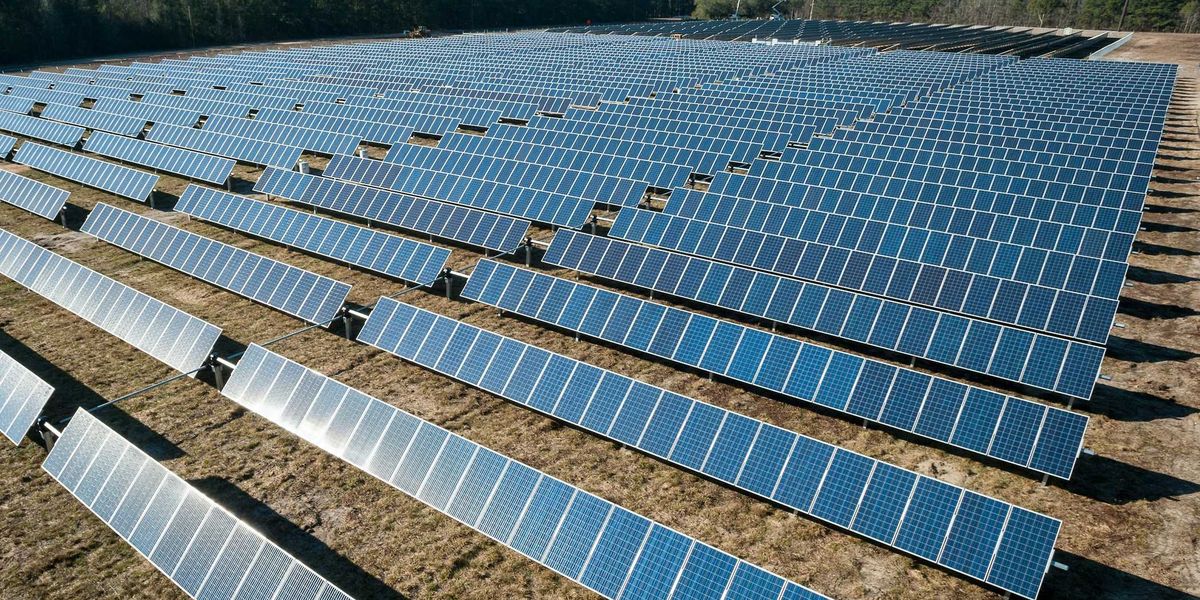 Rows of solar panel boards on brown ground.