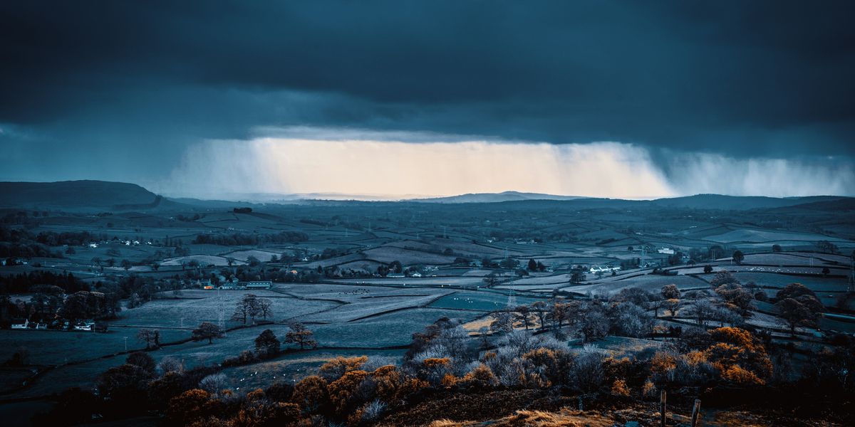 Rural hills under dark storm clouds during daytime.