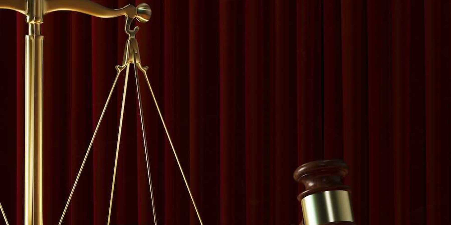 Scales of justice adjacent to a judges gavel signifying court ruling