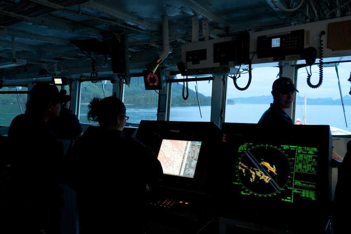 Scientific research vessel with 3 crew members surrounded by electronic instruments