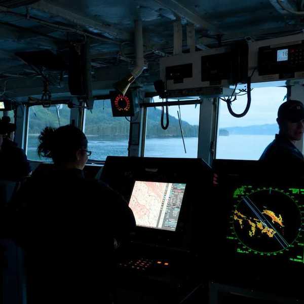 Scientific research vessel with 3 crew members surrounded by electronic instruments