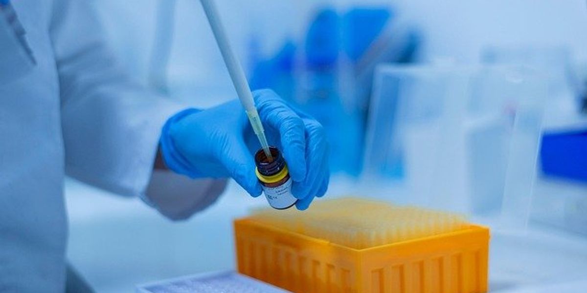 Scientist inserting pipette into a small bottle.