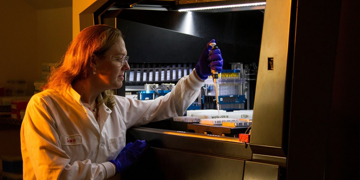 Scientist using pipette to place liquid into containers.