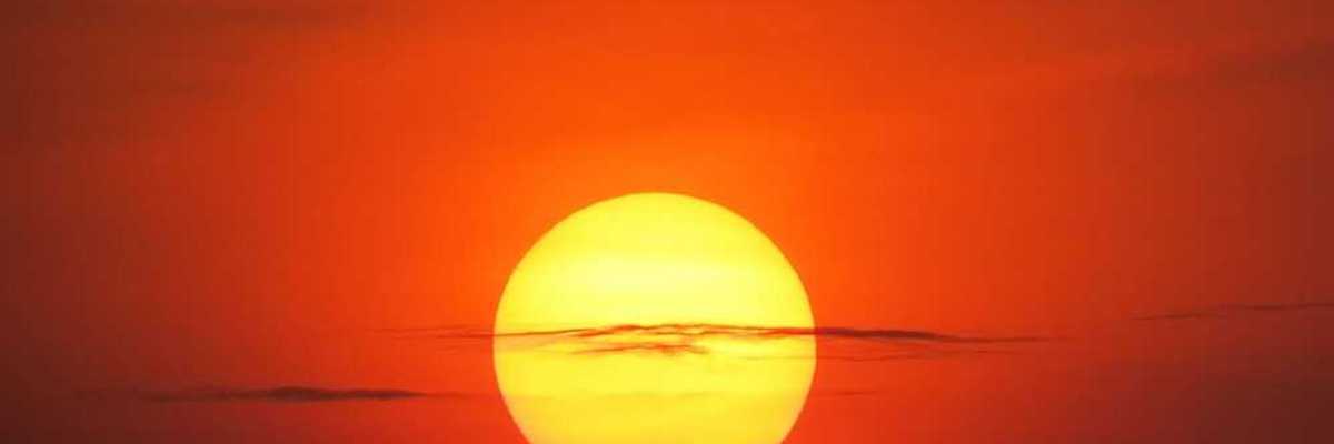Setting sun at dusk against a red-orange sky