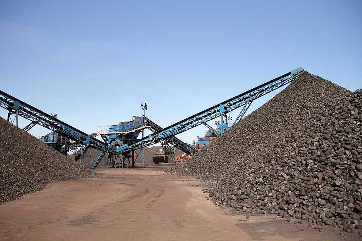 Several piles of coal with equipment in the background