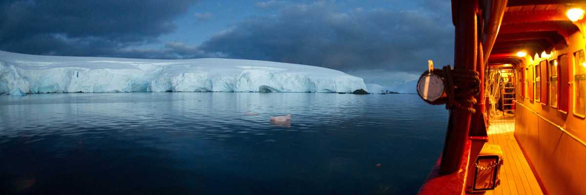 ship floating on ocean heading to ice burg