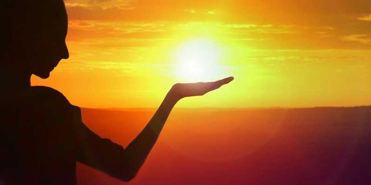 silhouette of a girl facing sunset, golden sky and water