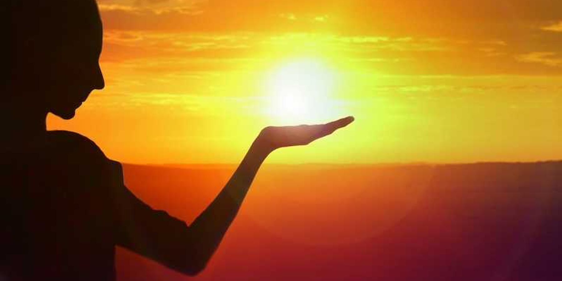 silhouette of a girl facing sunset, golden sky and water