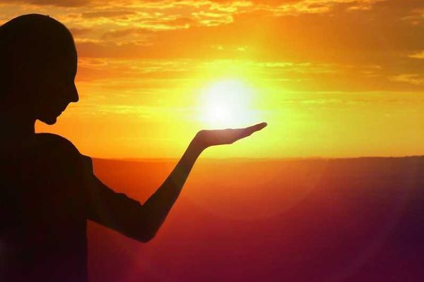 silhouette of a girl facing sunset, golden sky and water