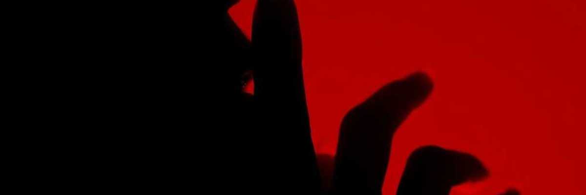 Silhouette of a person with finger to lips in a shushing gesture