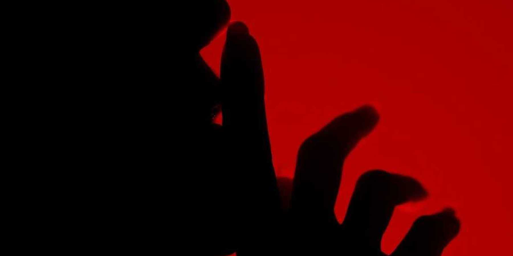 Silhouette of a person with finger to lips in a shushing gesture