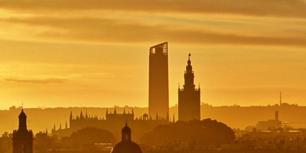 silhouette of buildings in Seville, Spain against a golden evening sky.