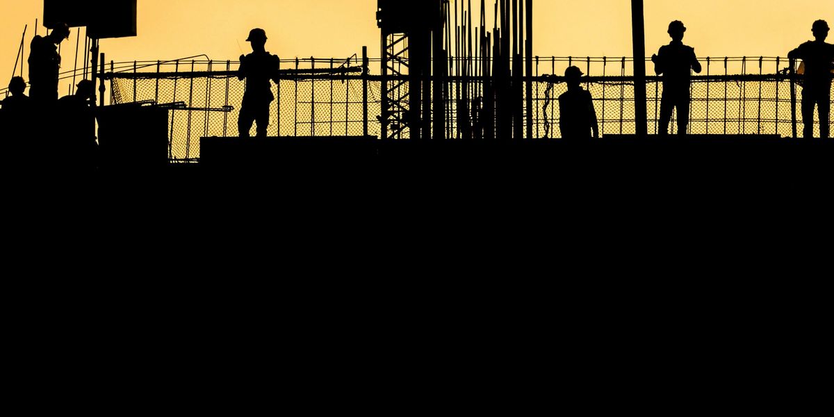 silhouette of people standing on tower crane during night time.