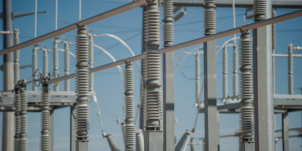 Silver electricity grid against a blue daytime sky.