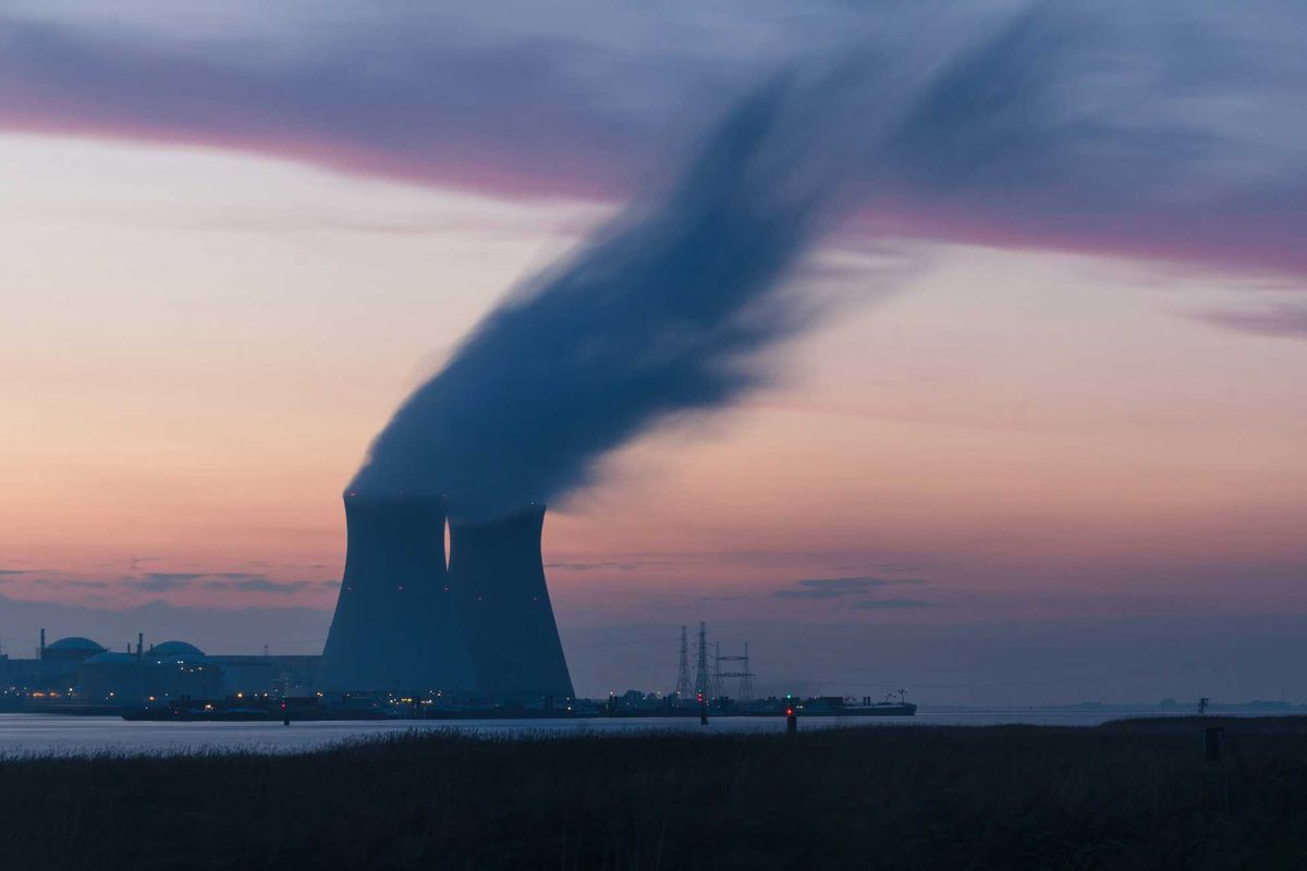skyline photography of nuclear plant cooling tower blowing smokes under white and orange sky at daytime.