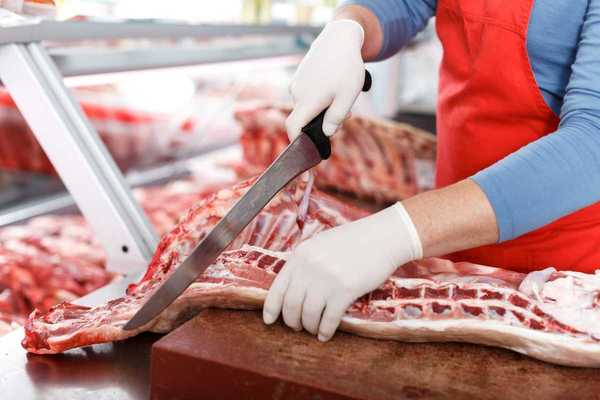 Slaughterhouse worker processing meat with a large knife