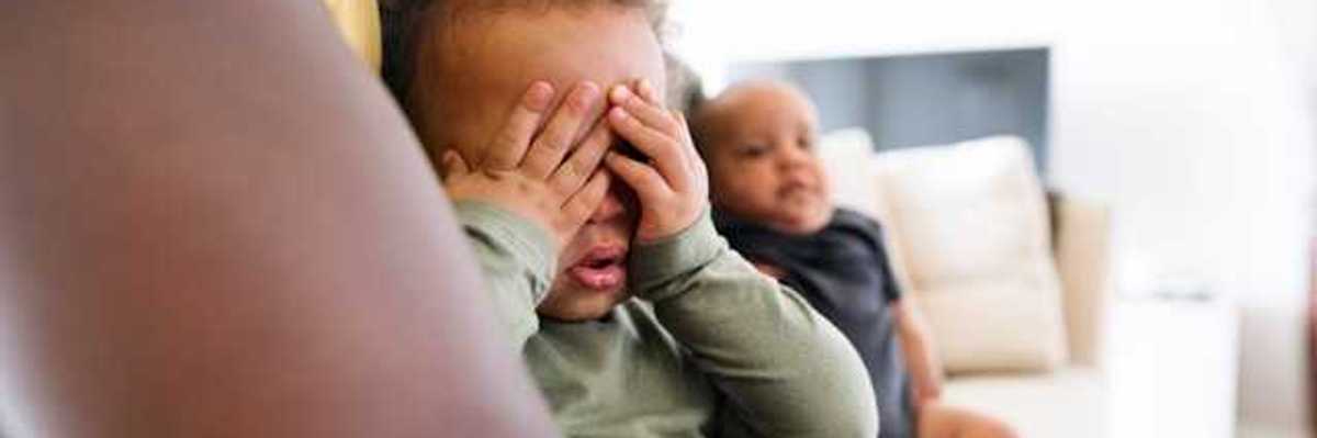 Small Black child sitting his fathers lap covering his eyes