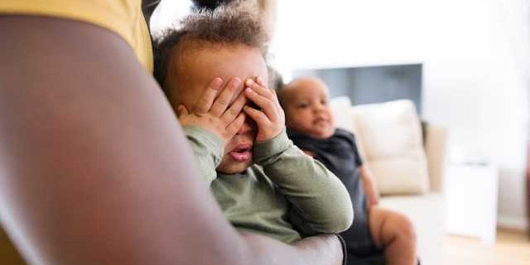 Small Black child sitting his fathers lap covering his eyes